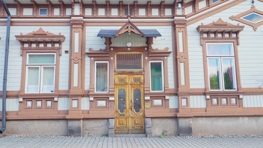 Ornate Wooden Doorway of a Historic Building in Rauma, Finland	A close-up view of an ornately carved wooden doorway on a historic building in Pori, Finland. The building is painted white with brown