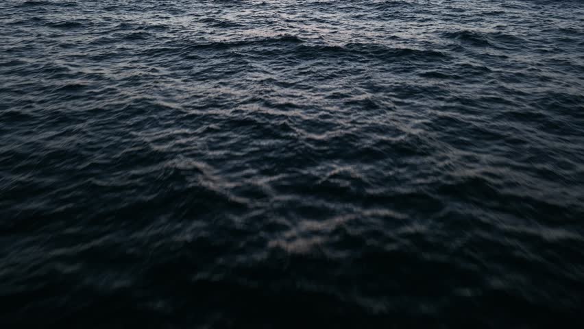 Drone shot of calm Ocean waves panning up motion. dramatic sunset.