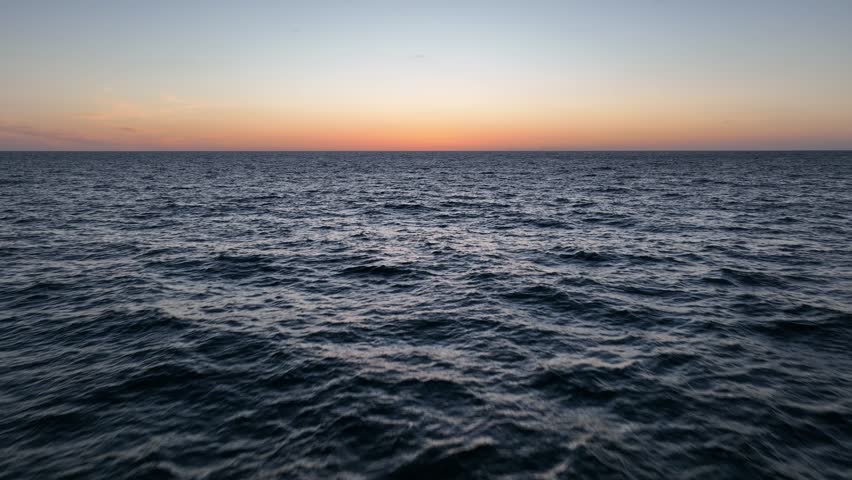 Drone shot of calm Ocean waves panning up motion. dramatic sunset.