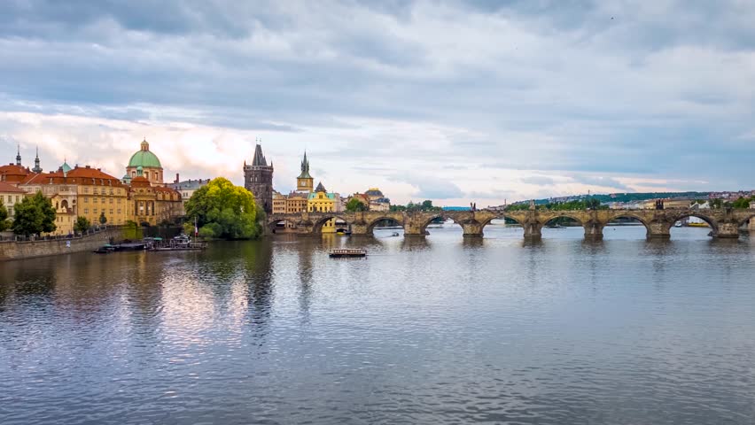 Motion sunset time lapse view of the cityscape of Prague with Charles Bridge, river Vltava and boat traffic, Czech Republic