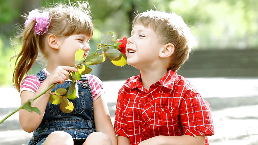 Two children speaking and boy presents flower