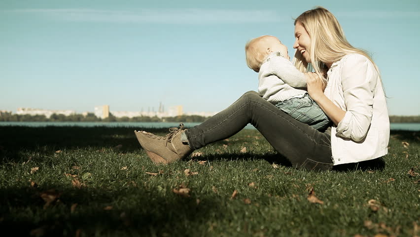 Baby playing with mother on the grass in park