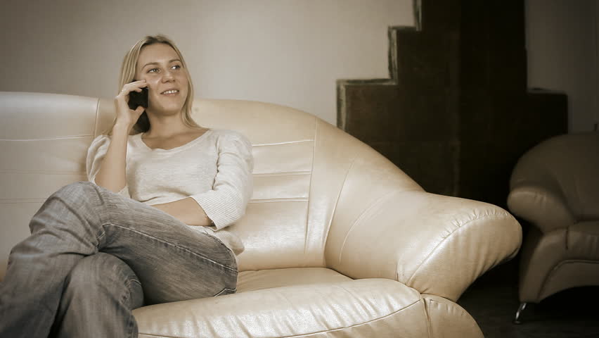 Beautiful girl on sofa, speaking on phone