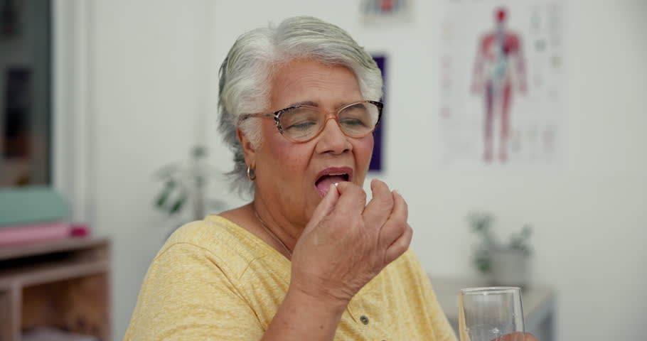 Pill, water and senior woman in clinic for medical consultation with medication for recovery of flu. Healthcare, vitamins and elderly female person with medicine, tablet or supplement with h2o drink.