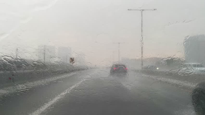 Rainwater falls on the front window of the car, driving in heavy rain, raindrops on the car window. concept of driving in the rain