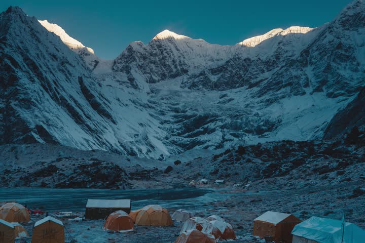 A breathtaking view of Mount Annapurna with a base camp in the foreground, capturing the serene beauty and majesty of the Himalayan mountains under clear skies.