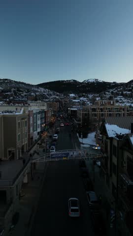 A drone footage of a pedestrian flyover bridge crossing a street in Park City at sunset during the winter in Utah, United States