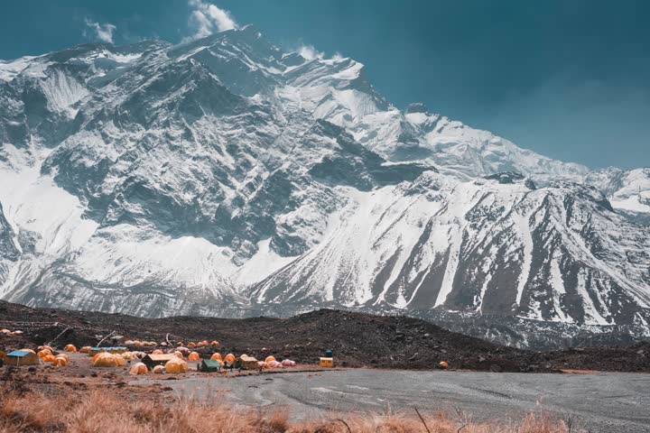 Expedition tents at the base of Mount Annapurna, Nepal, with towering snow-capped peaks in the background, capturing the essence of high-altitude adventure and mountaineering.