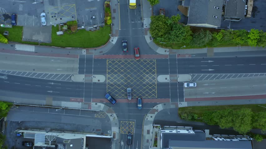 Cars arriving, stopping, and turning at a major four way intersection. Aerial top down bird's eye view overview.