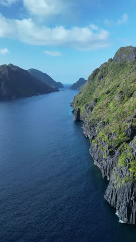 An aerial view of the coastal green rocky cliff of Matinloc Island on a sunny day in El Nido, Palawan, Philippines
