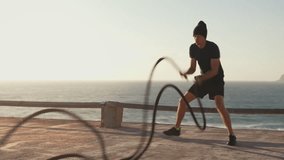 Athletic man fitness model training battle ropes against sea during sunset. Sport fitness healthy lifestyle concept. Caucasian person muscular body functional training endurance. - Powered by Shutterstock - Get 15% off with code: PIKWIZARD15