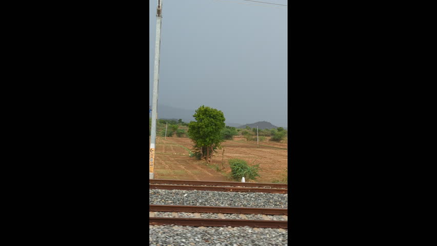 View of distant mountains through farms from a train