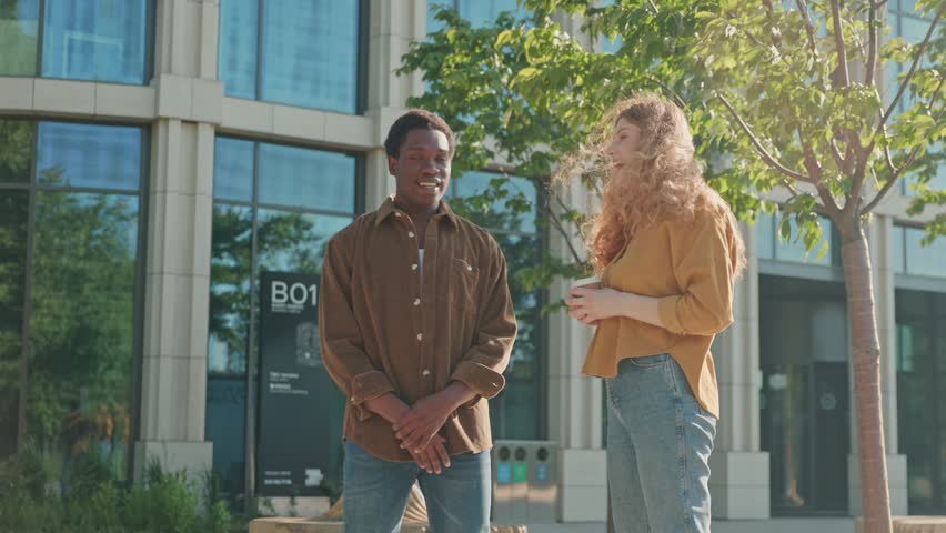 Three multiethnic colleagues having casting meeting. Multicultural people conducting business meeting in the city park. Agency director greeting colleague by hand. Stylish young people.
