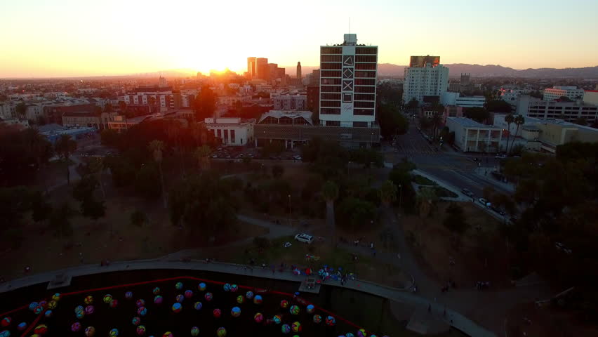 Aerial Tilt Down Shot Of Colorful Macarthur Park In Residential City By Mountains Against Clear Sky During Sunset - Los Angeles, California
