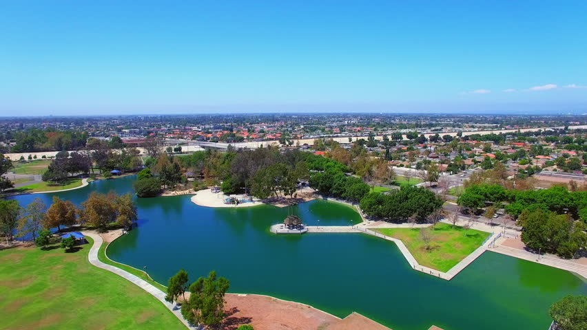 Aerial Forward Descending Beautiful Shot Of Pond In Centennial Park By Residential City On Sunny Day - Los Angeles, California