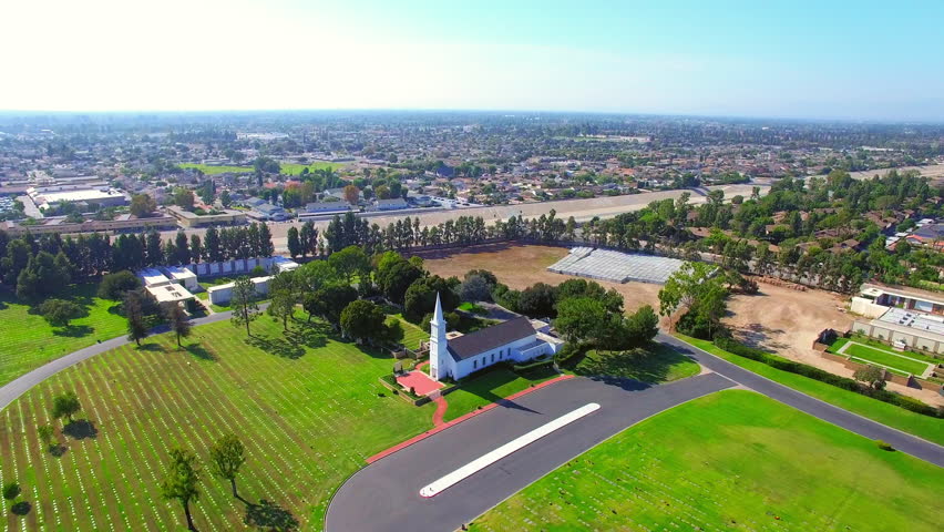 Aerial Tilt Down Shot Of Church On Green Landscape Of Memorial Park On Sunny Day - Los Angeles, California