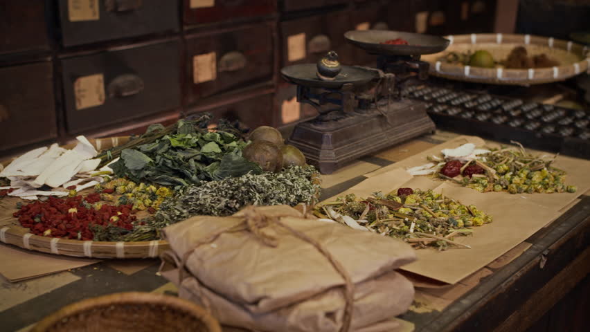 Handheld no people shot of chinese medicine ingredients, herbs and scales on table at drug store