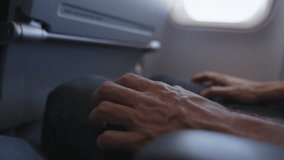 Fear of flying. Man on a plane grips his seat, visibly terrified of flying. Concept of aviophobia or aerophobia. He taps his fingers nervously, anxious for a safe landing and fearing a crash. - Powered by Shutterstock - Get 15% off with code: PIKWIZARD15