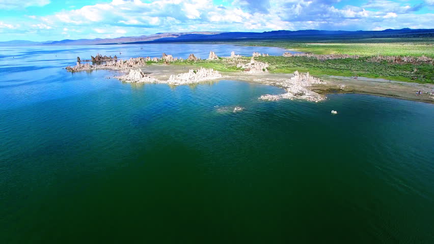 Aerial Forward Shot Of People Exploring Saline Soda Lake Under Clouds On Sunny Day - Lee Vining, California