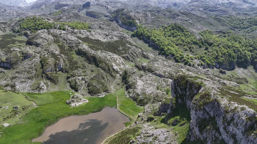 Covadonga lakes in Picos de Europa Panning up reveal snow capped mountains drone