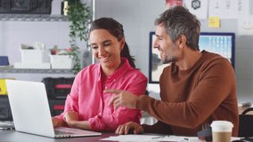 Businessman and businesswoman in creative office working at desk on laptop collaborating on project together - shot in slow motion - Powered by Shutterstock - Get 15% off with code: PIKWIZARD15