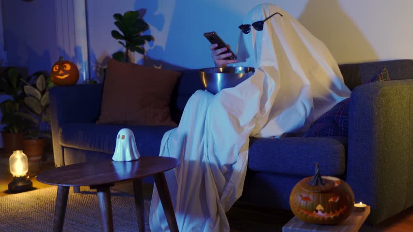 ghost with sunglasses and popcorn with pumpkins texting at halloween tv movie