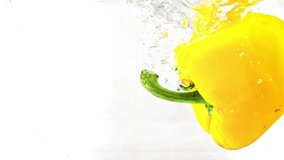 One yellow bell pepper is falling into water with splashes and bubbles filmed in macro against white background. Fresh paprika vegetable is thrown and washed in transparent aqua. Eat healthy food - Powered by Shutterstock - Get 15% off with code: PIKWIZARD15