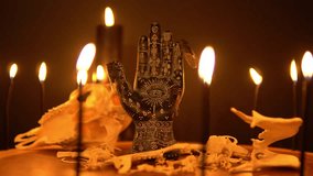 Black fortune teller hand with constellations on the reader table with magic animal bones, goat skull and cicada insects. Alchemy spirituality symbolic background with candle smoke and fog. - Powered by Shutterstock - Get 15% off with code: PIKWIZARD15