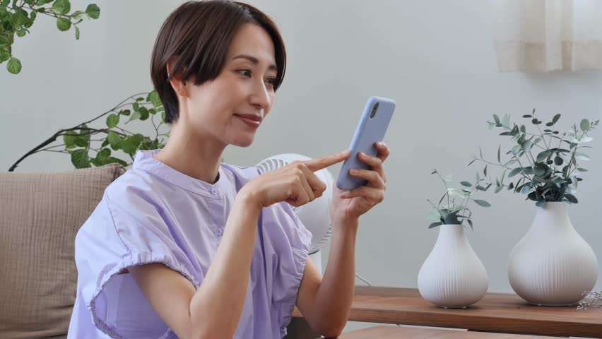 Asian middle aged woman using the smartphone in the living room