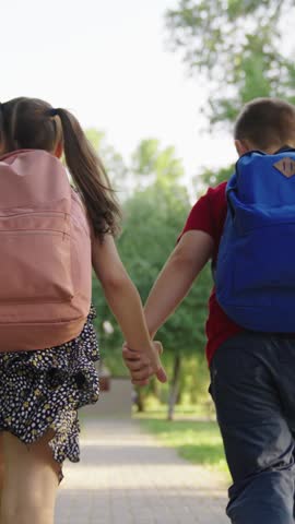 boy girl holding hands running through park school, child with school backpacks running along sidewalk school lesson, cheerful classmates running hand hand with bags, teamwork group children, boy girl