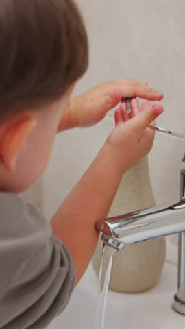 boy and baby child in bathroom,brushing teeth,washing hands with soap,combing hair.siblings,brothers in front of sink on tabouret chair.kids on toilet with lot of paper. sstkVertical