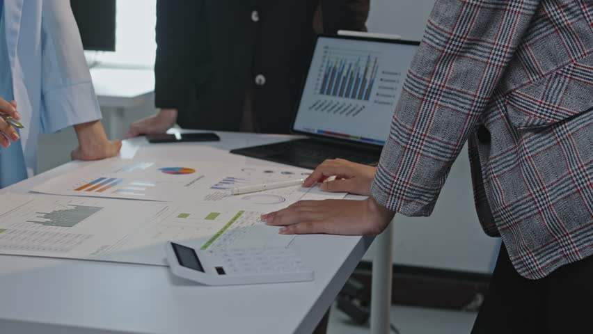 Diverse team discussing and analyzing financial charts and graphs in a professional office setting, focusing on collaboration and data analysis