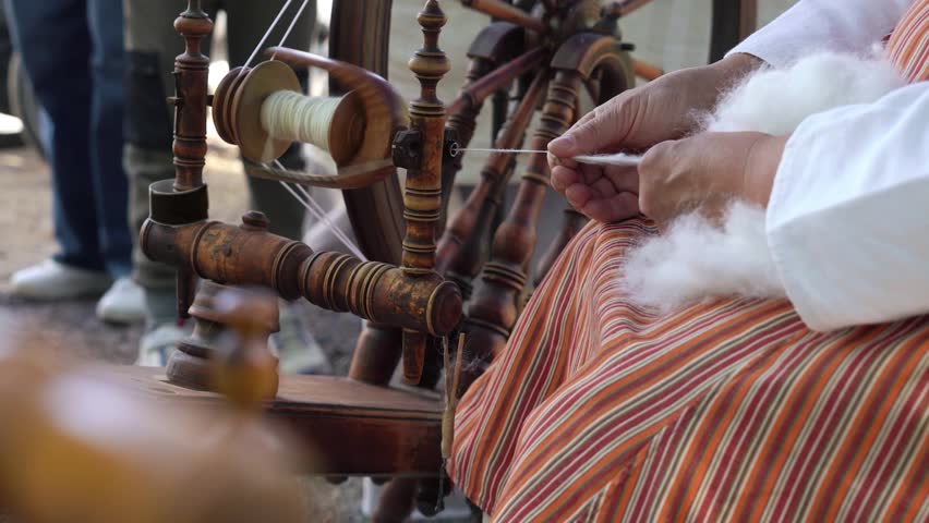 A woman in a Finnish traditional costume spins yarn using an ancient yarn machine