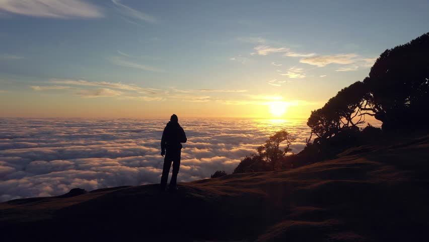 Silhouette of Standing Man on Hill at Sunrise. Cloud Inversion. Aerial Drone Shot. Madeira, Portugal. Moving Sideways
