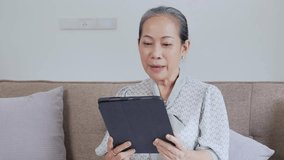 Elderly woman happily video chatting on a tablet at home, connecting with loved ones in a virtual meeting or family call - Powered by Shutterstock - Get 15% off with code: PIKWIZARD15