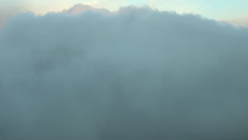 POV flying inside clouds with a pastel color sky at sunrise. Shot from an airplane cabin. 4K 60FPS