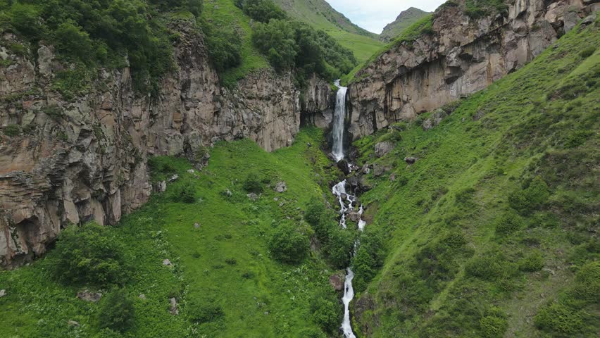 Aerial zoom in view Arsha waterfall stream in green caucasus mountains. KAzbegi national park. Things to see and do. Popular sightseeing hiking attraction. Georgia travel destination concept