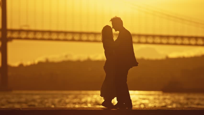 A couple is dancing in front of a bridge
