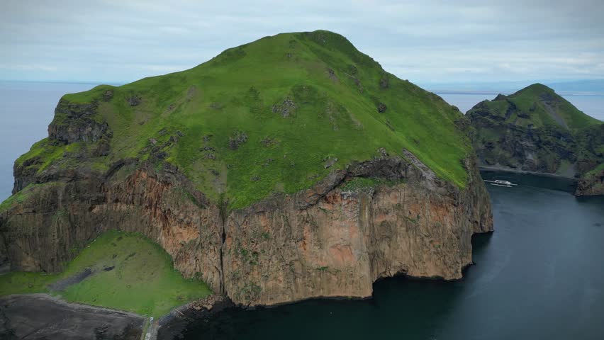 Aerial drone footage of an Icelandic mountain in Vestmannaeyjar near the ocean.