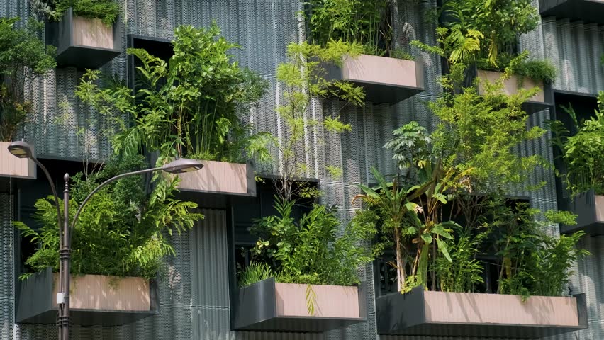 Building facade with green plants growing on balcony. Vertical garden in Kuala Lumpur city, Malaysia. Sustainable modern and ecological architecture