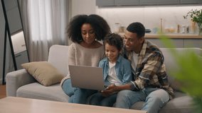 Smiling African American ethnic family male man dad woman mom female little boy child son kid recording blog using laptop online video notebook call distant learning watching TV show living room couch - Powered by Shutterstock - Get 15% off with code: PIKWIZARD15
