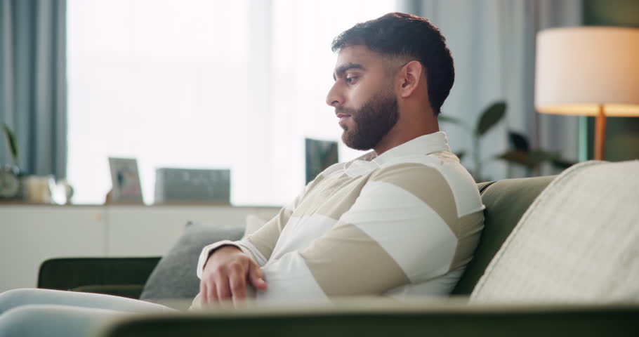 Thinking, relax and man on sofa for regret, decision or relationship mistake in living room. Thoughtful, home and Indian person for problem solving, reflection or remorse from communication issues