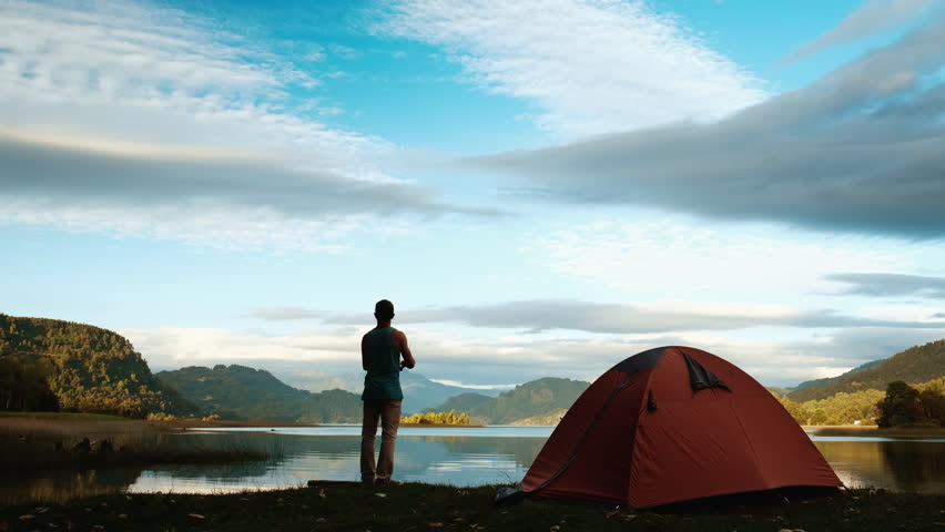 Man fishing on the lake and casting a lure on the lake with camping tent on the foreground