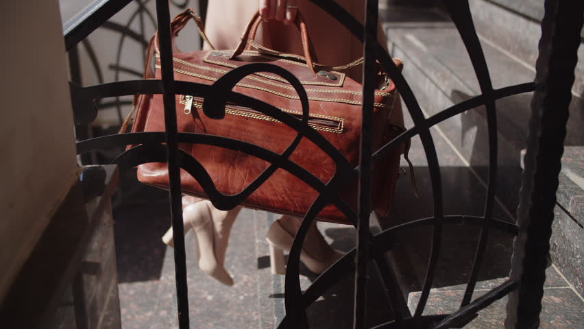 a girl in heels with a travel bag in her hands is climbing the stairs close up