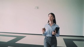 A business woman is walking up to escalator with a coffee cup in her hand. She is wearing a blue shirt and gray pants - Powered by Shutterstock - Get 15% off with code: PIKWIZARD15