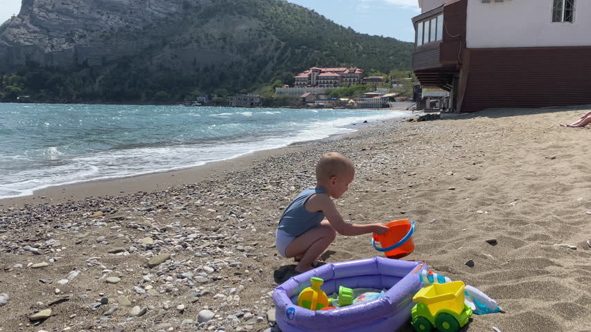 child little boy playing on empty beach in Novy Svet resort village, Crimea, Russia 2024
