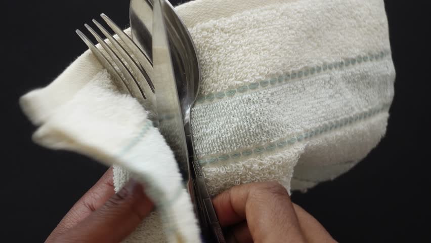  person hand cleaning and drying cutlery with a towel
