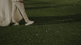 Bride and groom walking on the grass at night, with the bride's gown trailing behind - Powered by Shutterstock - Get 15% off with code: PIKWIZARD15