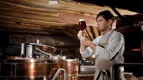 Brewer in apron tasting fresh beer. Handsome young male tasting fresh brewed beer. Beer production concept. Brewing - Powered by Shutterstock - Get 15% off with code: PIKWIZARD15