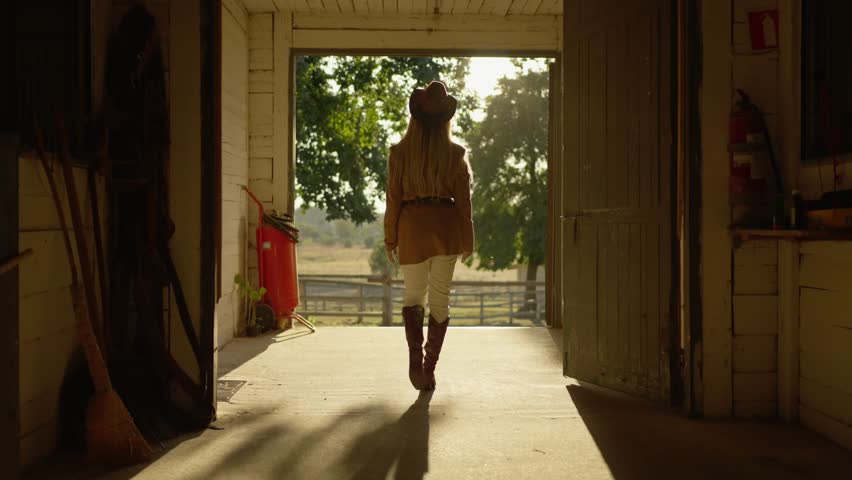 Woman in cowboy hat leaves cow farm. Horse riding concept.